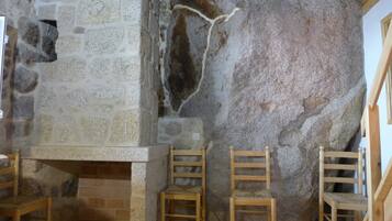 A stone wall with a fireplace, wooden chairs, and a wooden bench.