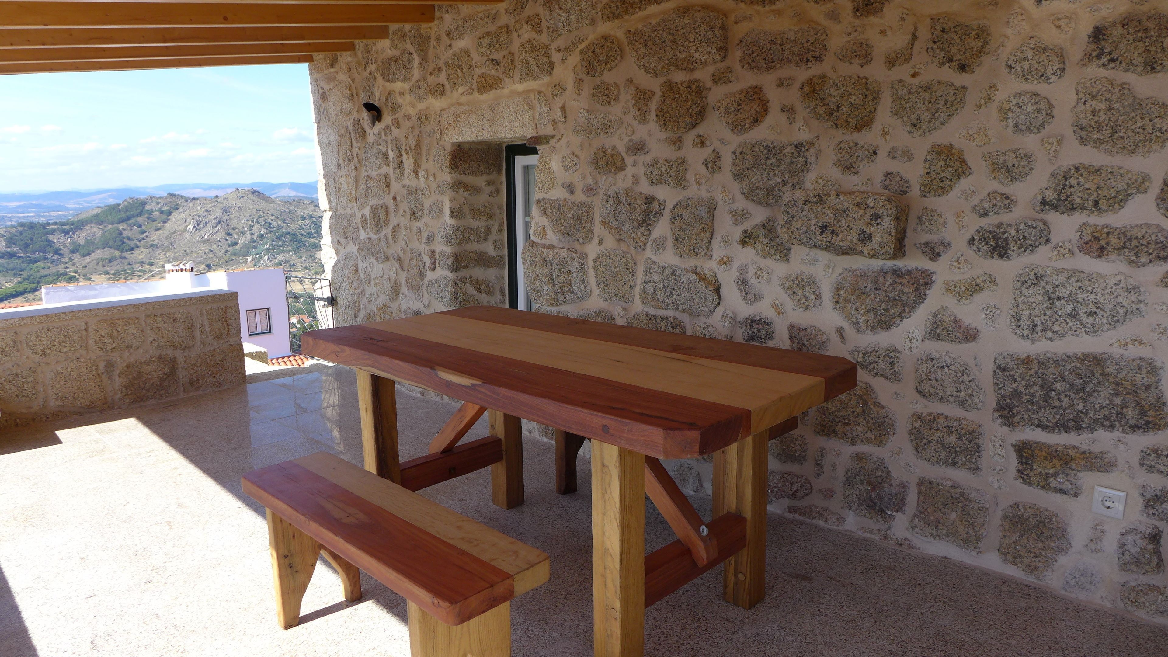 A stone wall with a wooden table and bench.