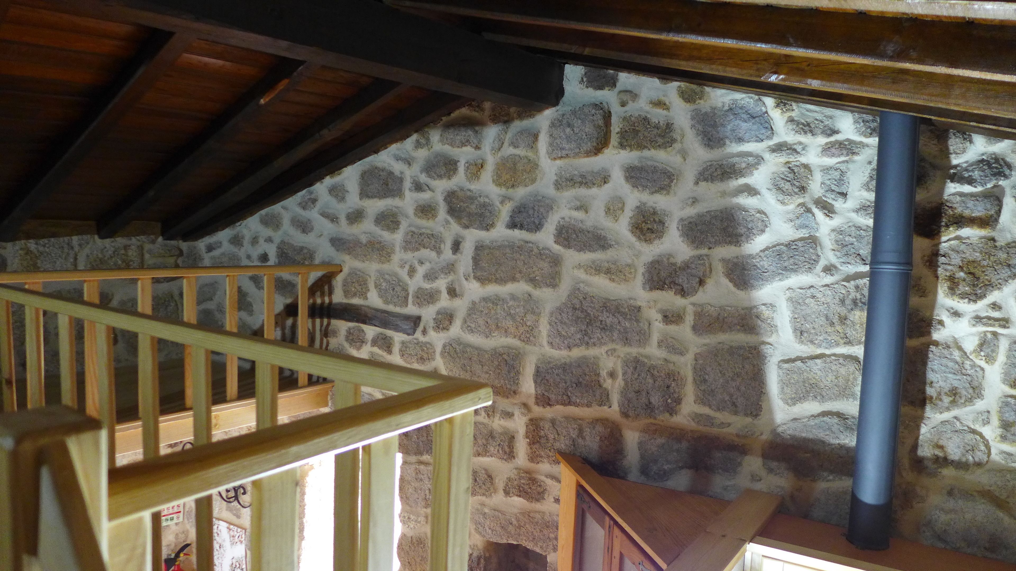 Un muro in pietra con una scala di legno e un tubo in metallo.
