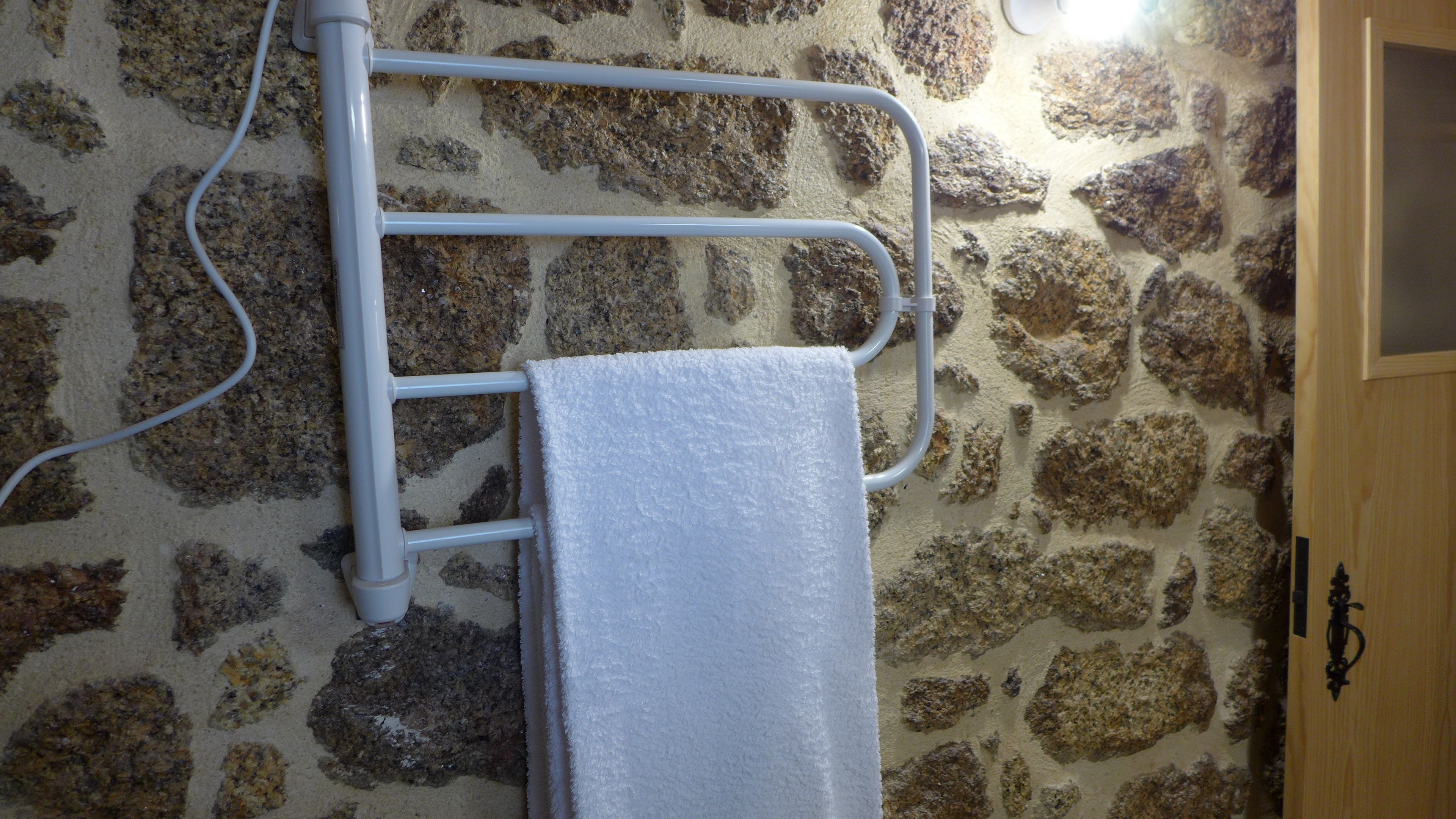 A towel rack against a stone wall with a wooden door to the right.