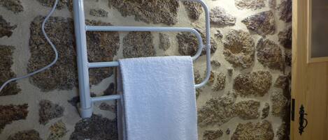 A towel rack against a stone wall with a wooden door to the right.