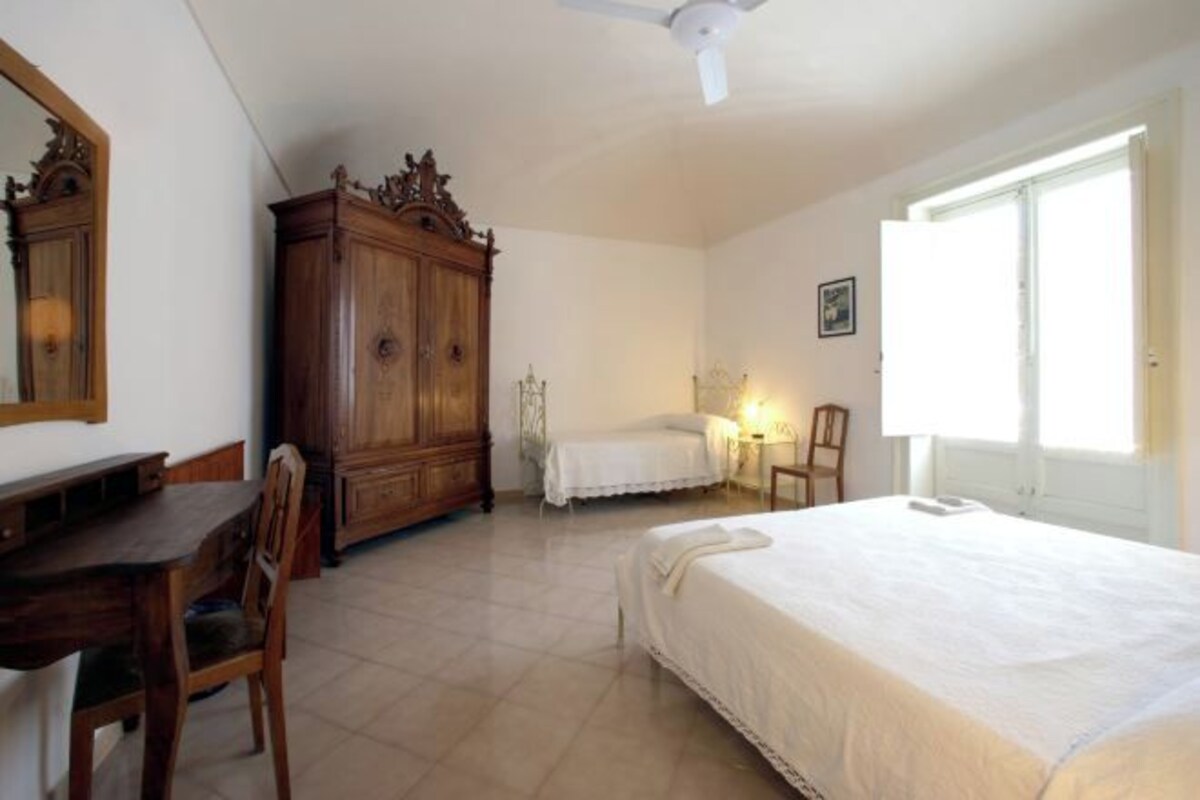 A bedroom with a bed, a desk, a wardrobe, and a chair.