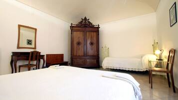Ein Schlafzimmer mit einem großen Bett, einem Holzschrank, einem Schreibtisch mit Stuhl und einem Nachttisch mit Lampe.