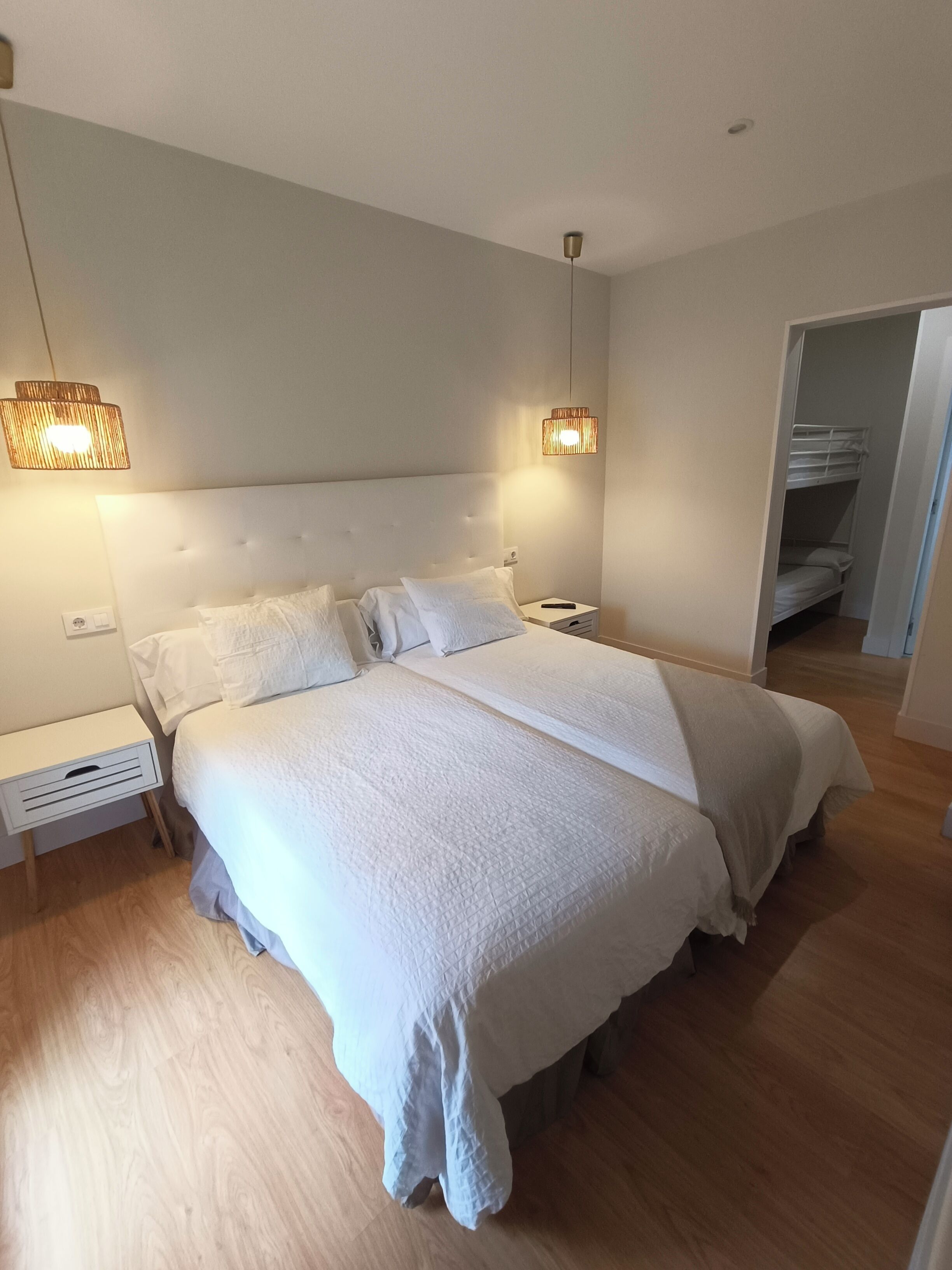Un dormitorio ordenado con una cama grande, mesitas de noche y un armario.