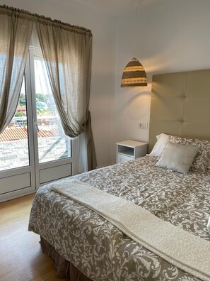 A bedroom with a bed, a nightstand, a lamp, and a window with curtains. - Hotel Posada del Mar (Suances)