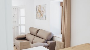 A modern living room with a beige sofa, a wooden coffee table, and a white wall with a painting. - Hotel Posada del Mar (Suances)