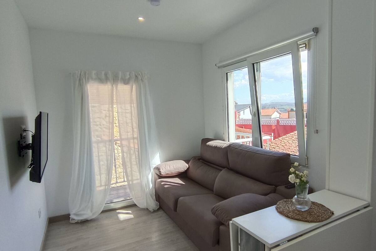 A modern living room with a brown sofa, a white coffee table, and a TV mounted on the wall.