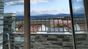 A balcony with a stone wall and a view of a cityscape and mountains. - Hotel Posada del Mar (Suances)