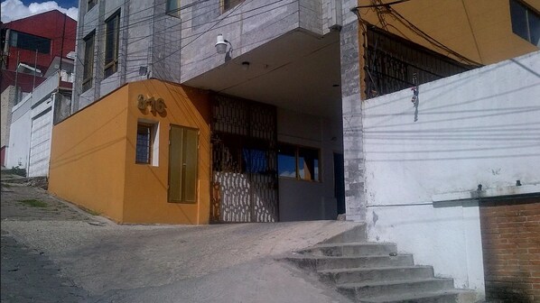 A building with a yellow facade, a gated entrance, and a staircase leading to a door. - Casa Villaliz (Toluca)