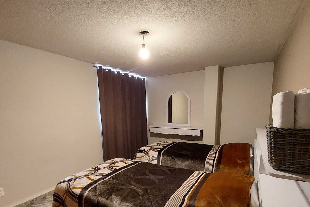 A bedroom with a bed, a mirror, a ceiling light, and a washing machine.