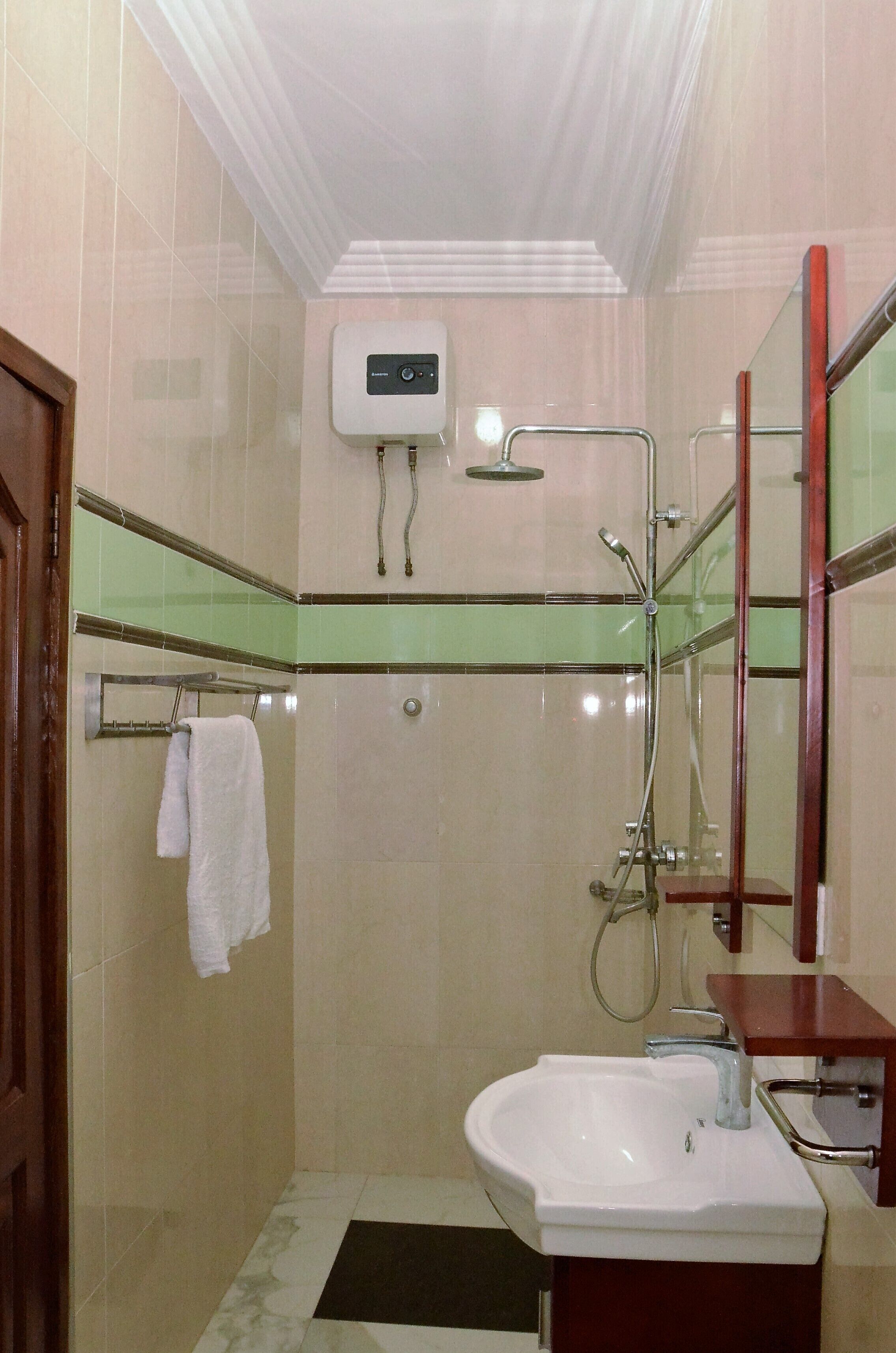 Une salle de bain avec un lavabo blanc, une cabine de douche en verre et une serviette suspendue à un porte-serviettes.