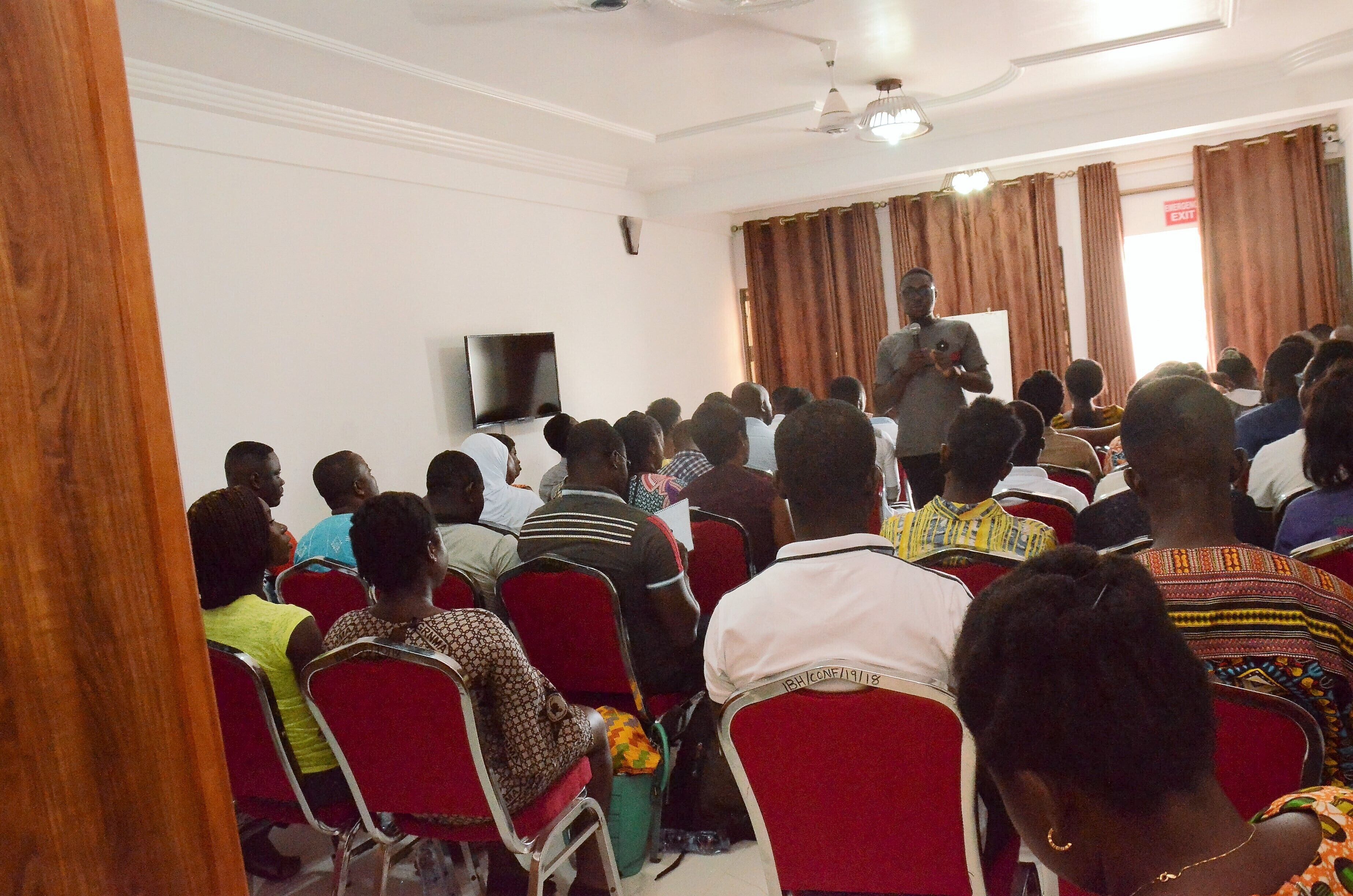 A conference room with attendees seated facing a speaker at the front.