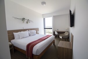 Una habitación de hotel moderna con una cama grande, un escritorio y una silla.