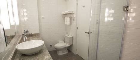 Un baño moderno con un lavamanos grande, inodoro y cabina de ducha de vidrio.