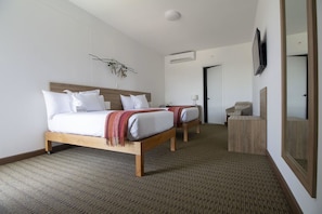 A hotel room with two beds, a TV, a mirror, and a small seating area. - Tierra Viva Piura (Piura)