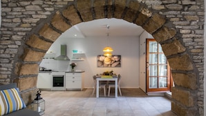 Een moderne keuken met witte kasten, een ingebouwde oven en een eethoek met een tafel en stoelen.