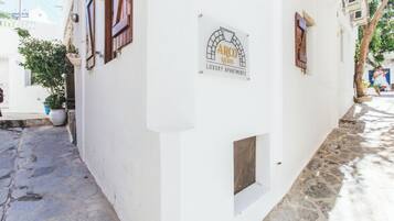 Un bâtiment blanc avec une enseigne indiquant « ARCO NAXOS, APPARTEMENTS DE LUXE ».