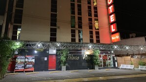 Et hotel med et markant rødt skilt, en overdækket indgang og et skilt der reklamerer med særlige grupperater.