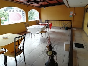 A dining area with tables and chairs, a flower vase, and a sign for a bed and breakfast.