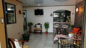 A spacious room with a dining area, a kitchen, and a seating area with chairs and tables. - Hospedaje Yaldai (Turrialba)