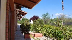 Un bâtiment en briques doté d’un patio couvert et de plantes en pot.