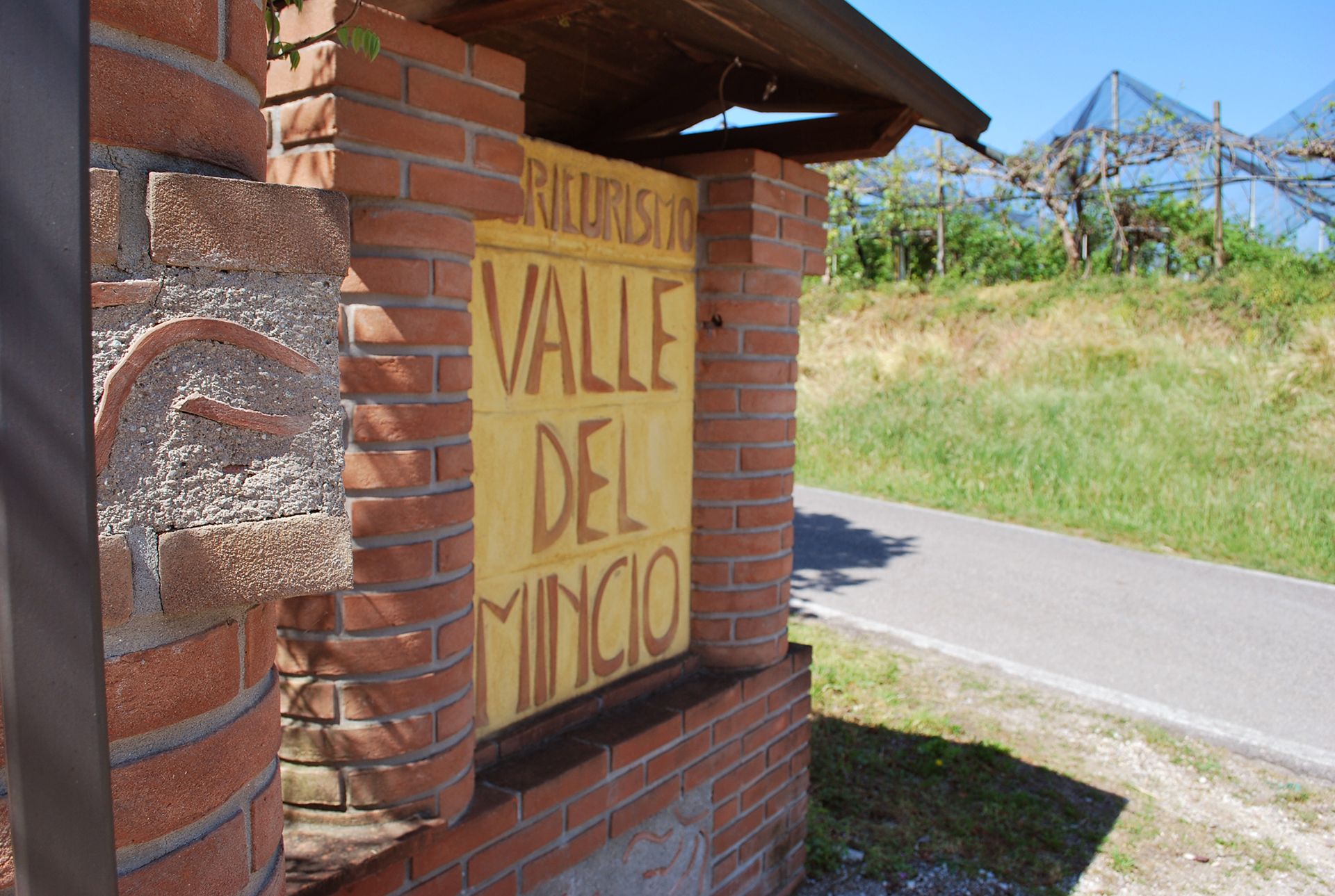 A brick wall with a yellow sign reading "RIEURISMO VALLE DEL MINGO".