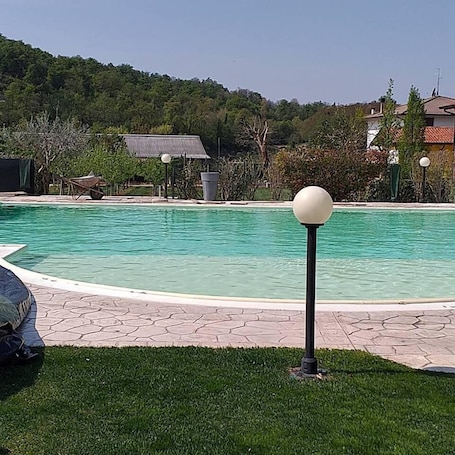 Una piscina al aire libre, sombrillas, sillones reclinables de piscina