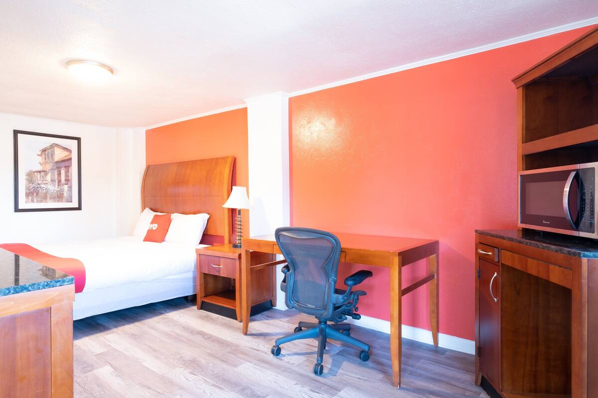 Une chambre d’hôtel équipée d’un lit, d’un bureau, d’une chaise et d’un four à micro-ondes.