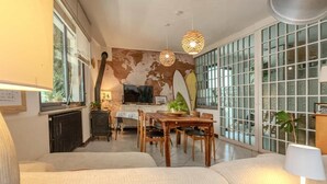Una sala de estar acogedora con un ventanal grande, chimenea y comedor con mobiliario de madera.