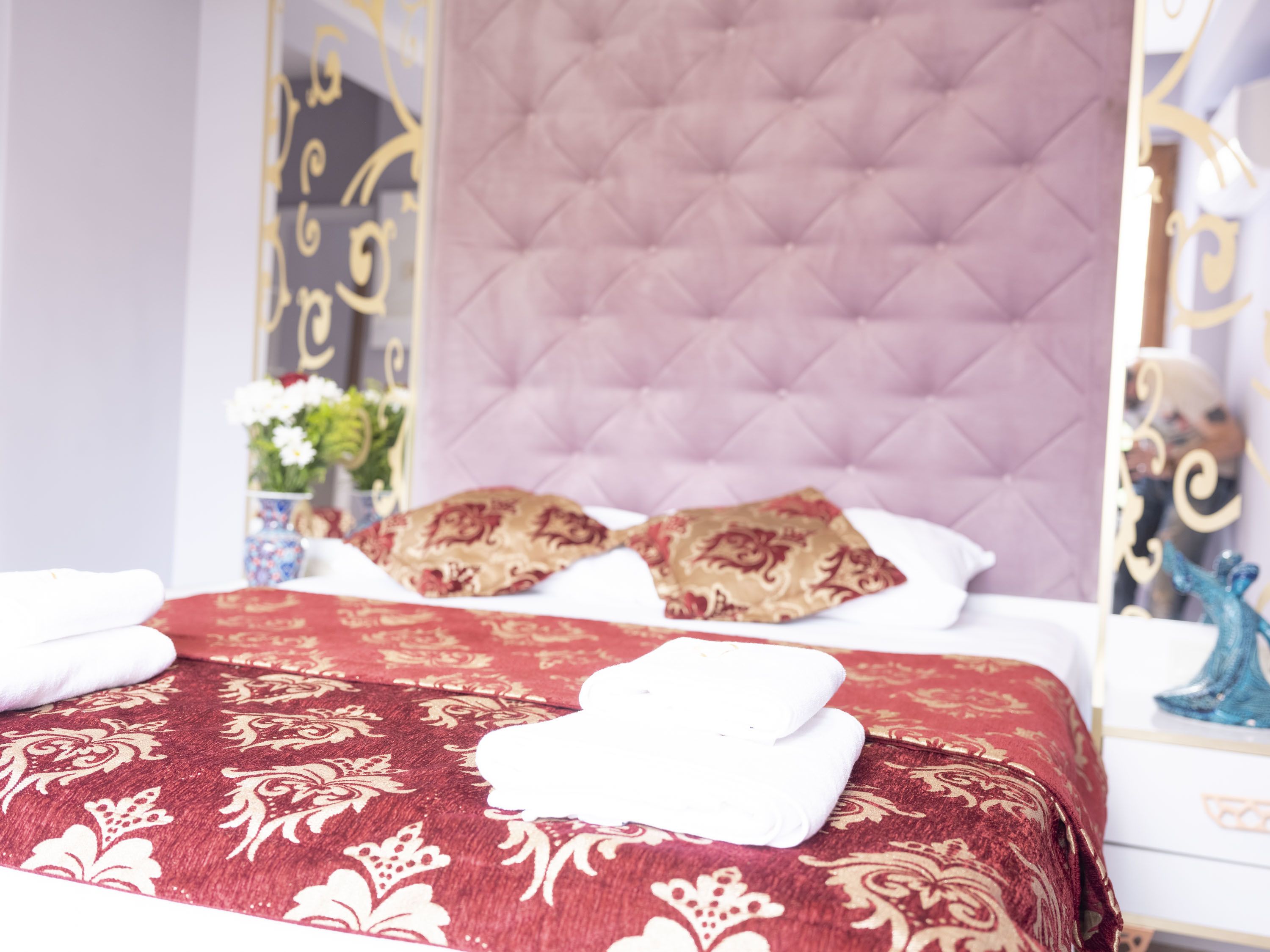 Ein Hotelzimmer mit einem großen Bett, einem gesteppten Kopfteil und einem dekorativen Spiegel.