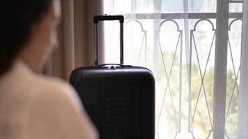 A person sitting by a window with a suitcase and a laptop.