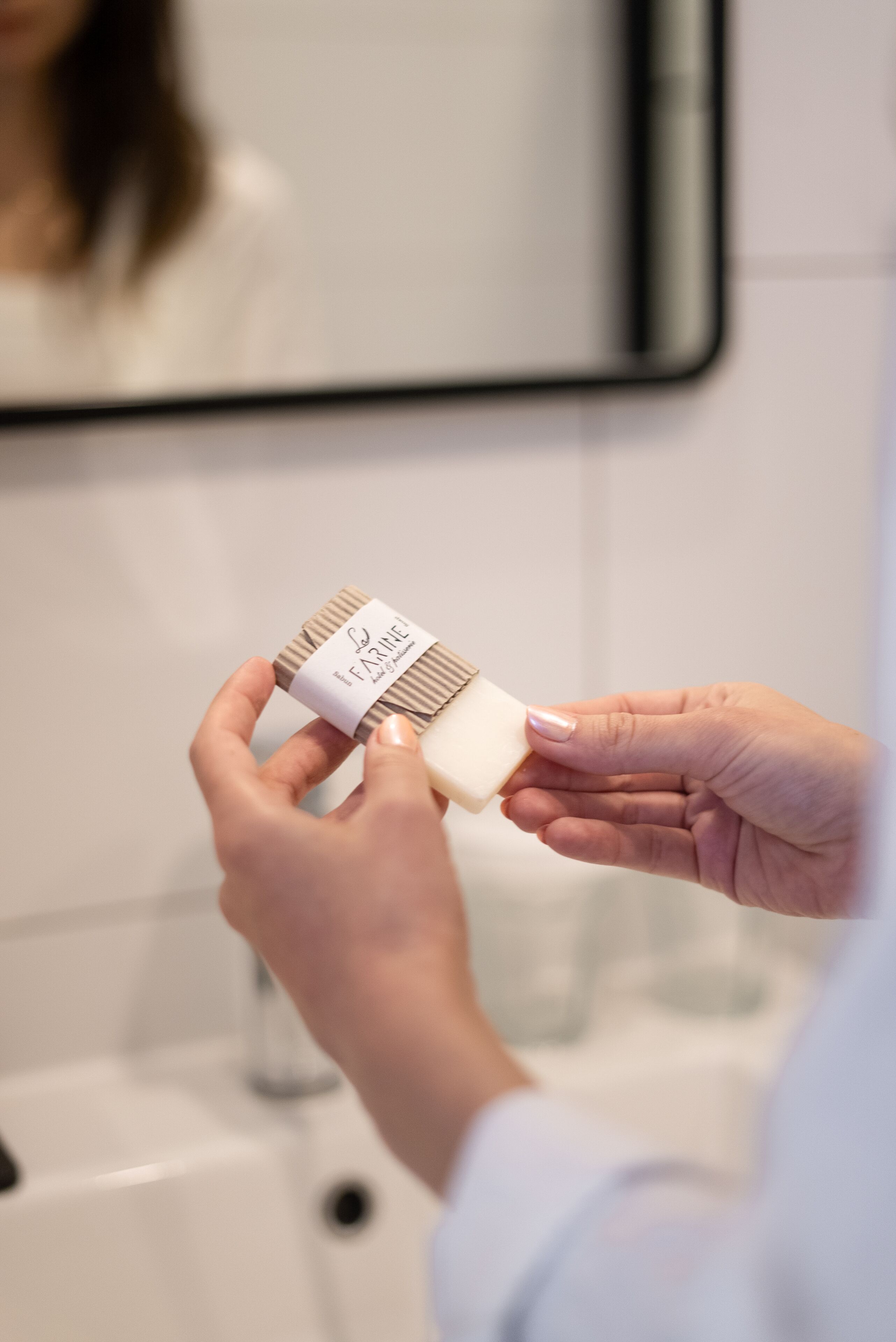 A person holding a small container with a label.