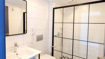 A modern bathroom with a white sink, toilet, and shower.
