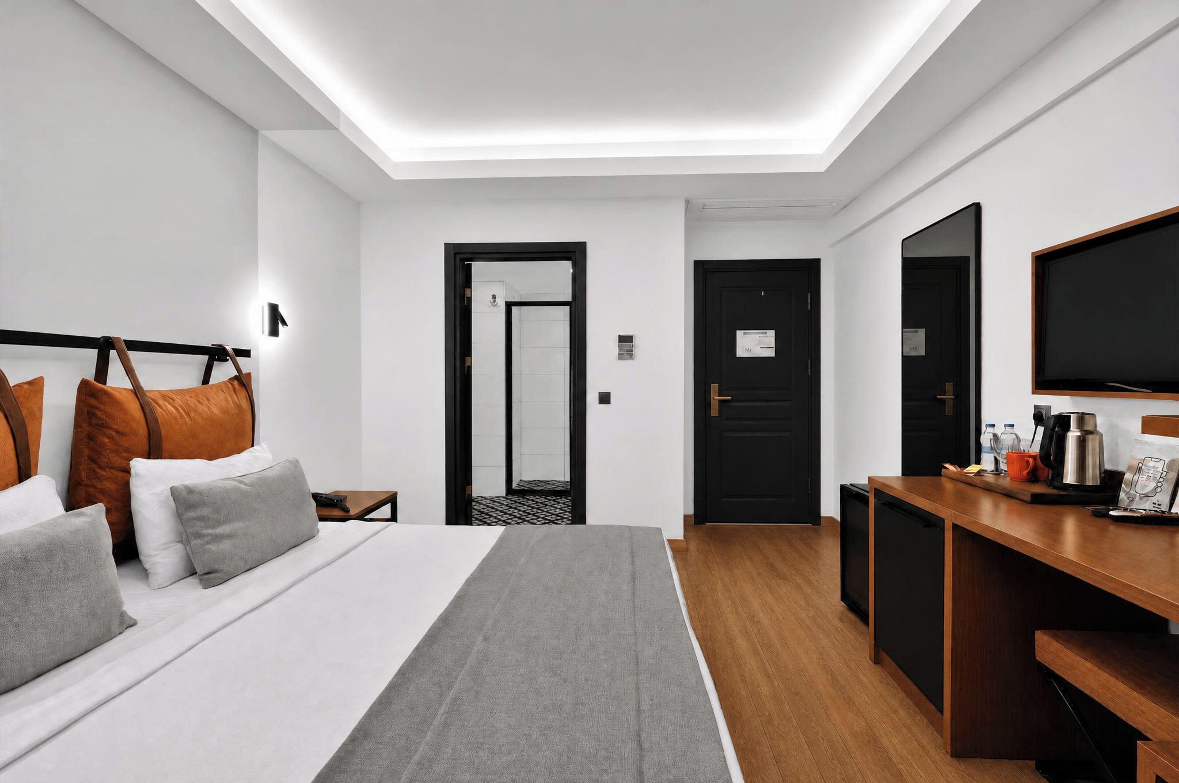 A hotel room with a bed, bedside table, desk, and a television.