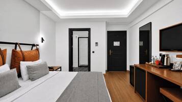 A hotel room with a bed, bedside table, desk, and a television.