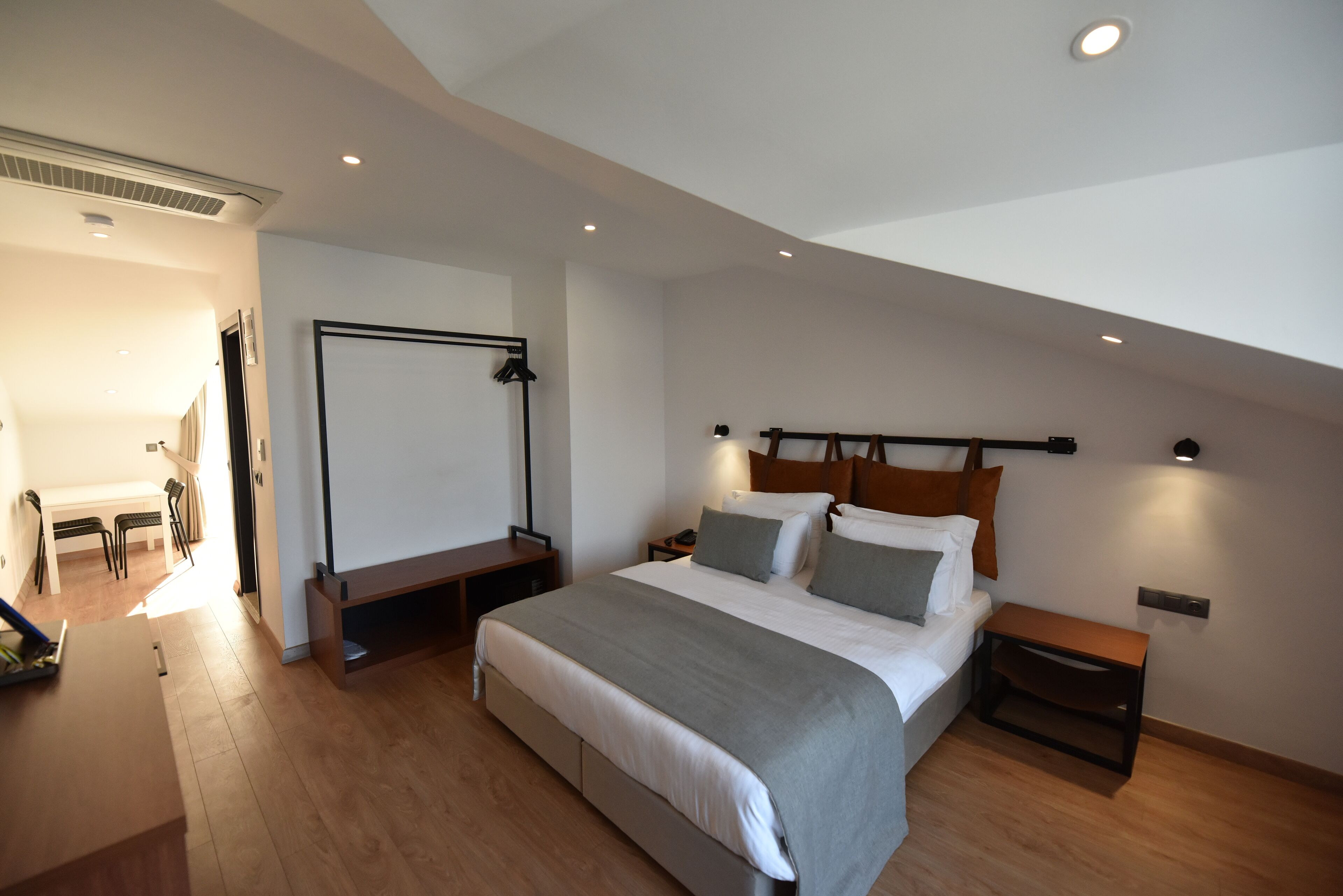 A modern bedroom with a large bed, bedside tables, a desk, and a chair.