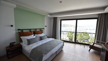 Une chambre moderne avec un grand lit, une petite table et un balcon offrant une vue sur la ville.