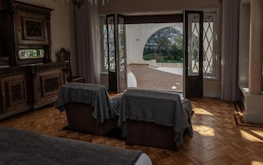 A room with a wooden floor, two upholstered chairs, a cabinet with a mirror, and a view of a brick pathway leading outside. - Espinho Vintage (Espinho)