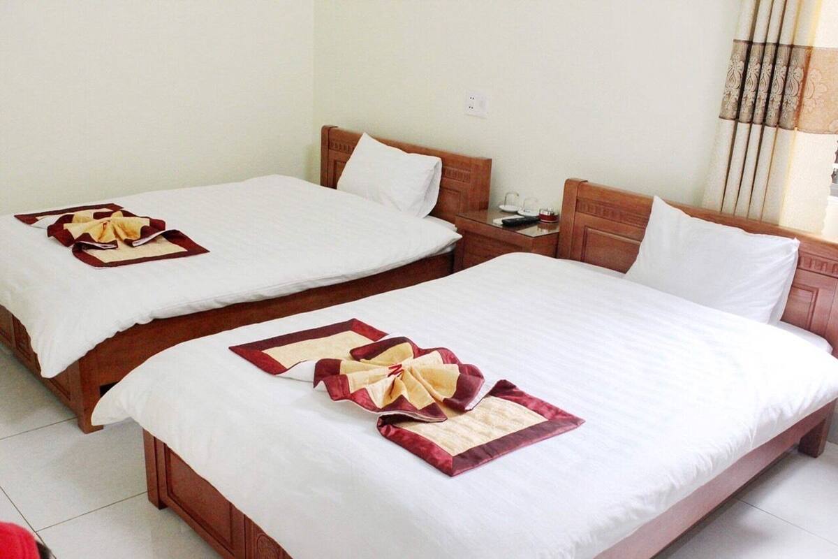 Two double beds with white linens and red decorative pillows.