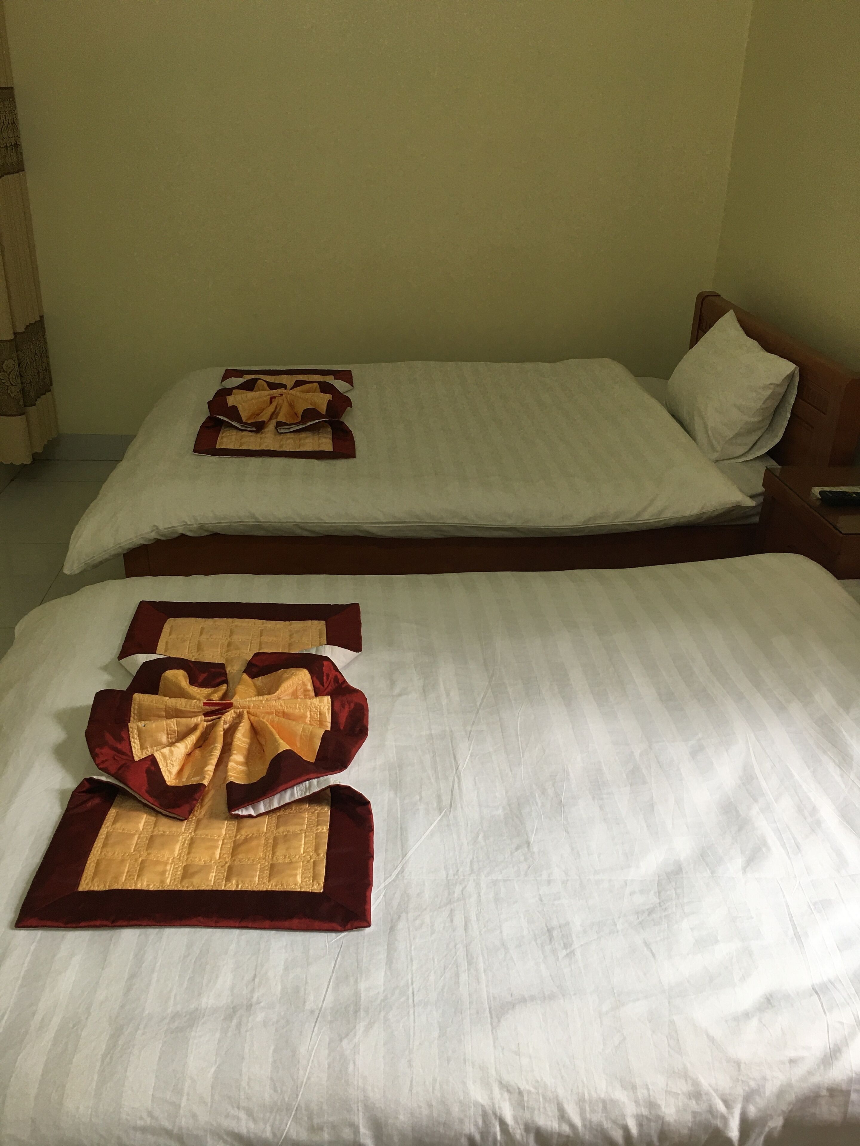 Two twin beds with white linens and decorative gold and red headboards.