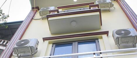 A building with multiple air conditioning units, a balcony, and a window.