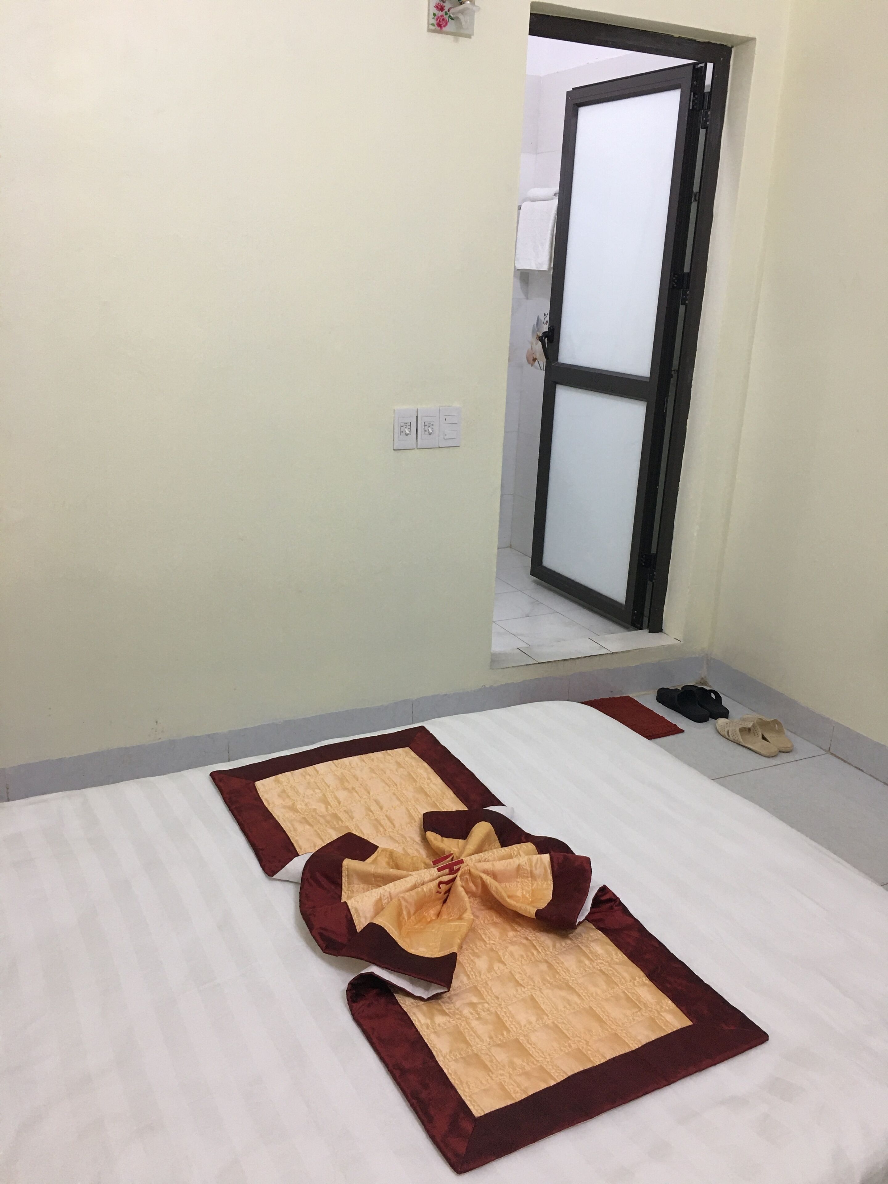 A hotel room with a bed, a door, and a pair of slippers on the floor.