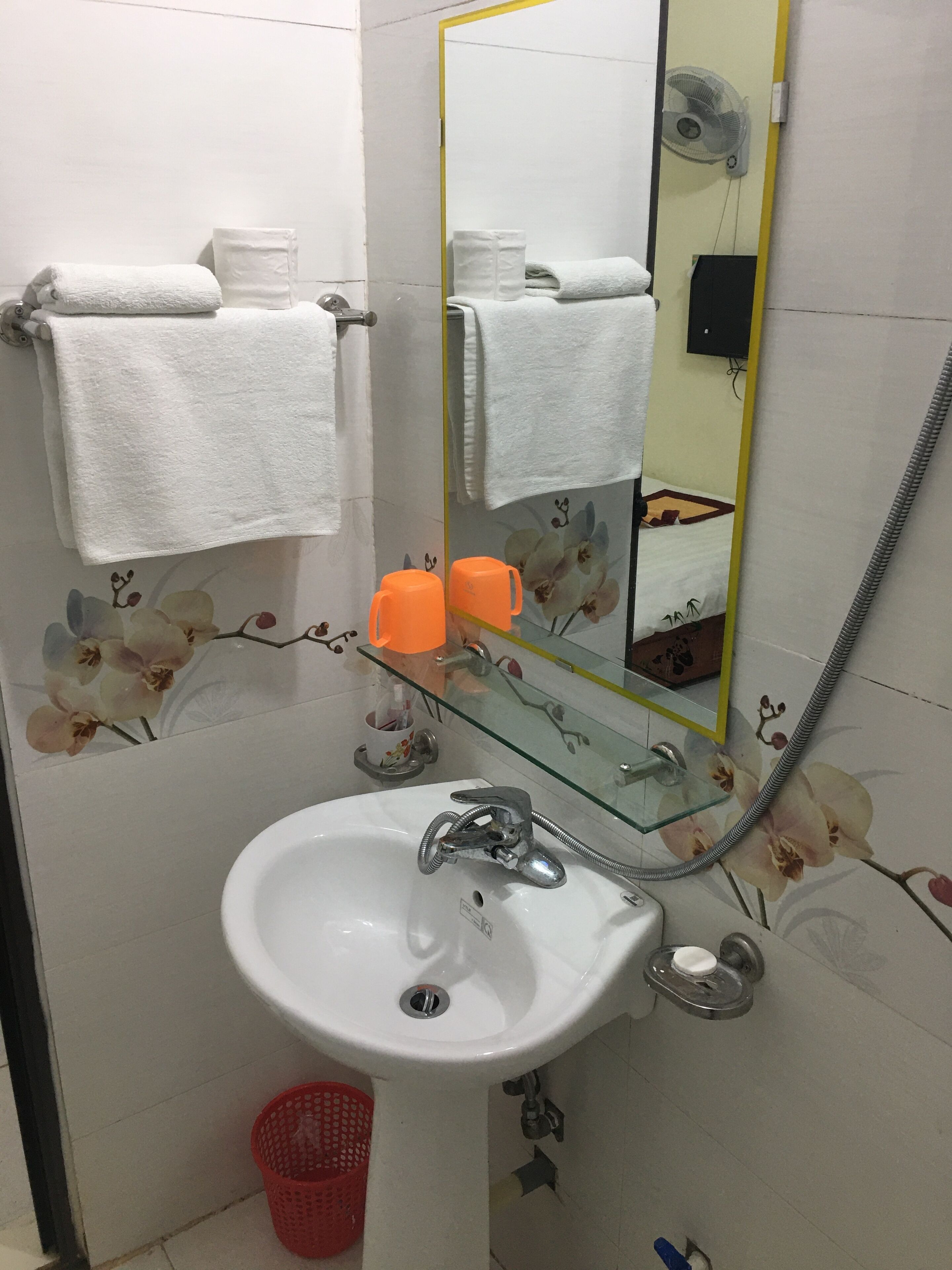 A bathroom with a white sink, a glass shower enclosure, and a mirror with a yellow frame.