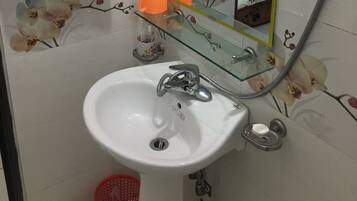 A bathroom with a white sink, a glass shower enclosure, and a mirror with a yellow frame.