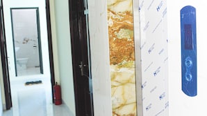 A corridor with a door leading to a bathroom, a fire extinguisher, and a wall with a patterned design. - Duc Thang Guest House (Dien Bien Phu)