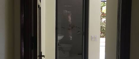 A hallway leading to a bathroom with a toilet and sink.