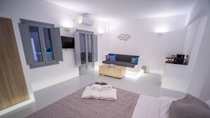 Um quarto moderno com uma cama grande, um sofá, uma mesa de centro e uma televisão.