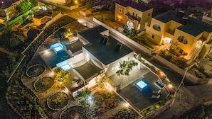 Vista aérea de um bairro residencial com piscina, jardins bem cuidados e casas vizinhas.