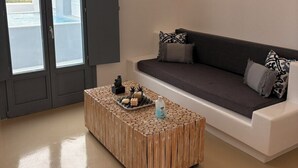 Uma sala de estar moderna com um sofá cinza, uma mesa de centro de madeira e um aparelho de luz fixado na parede.