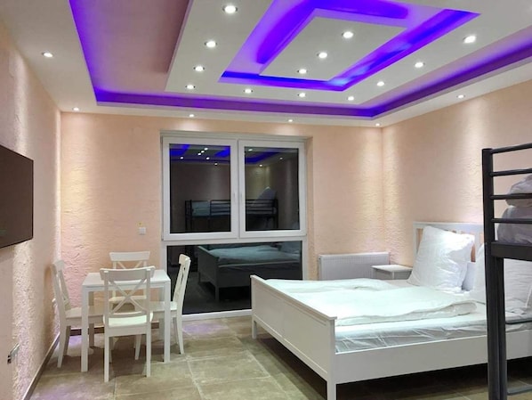 Un dormitorio con una cama nido, un escritorio con silla y una ventana.